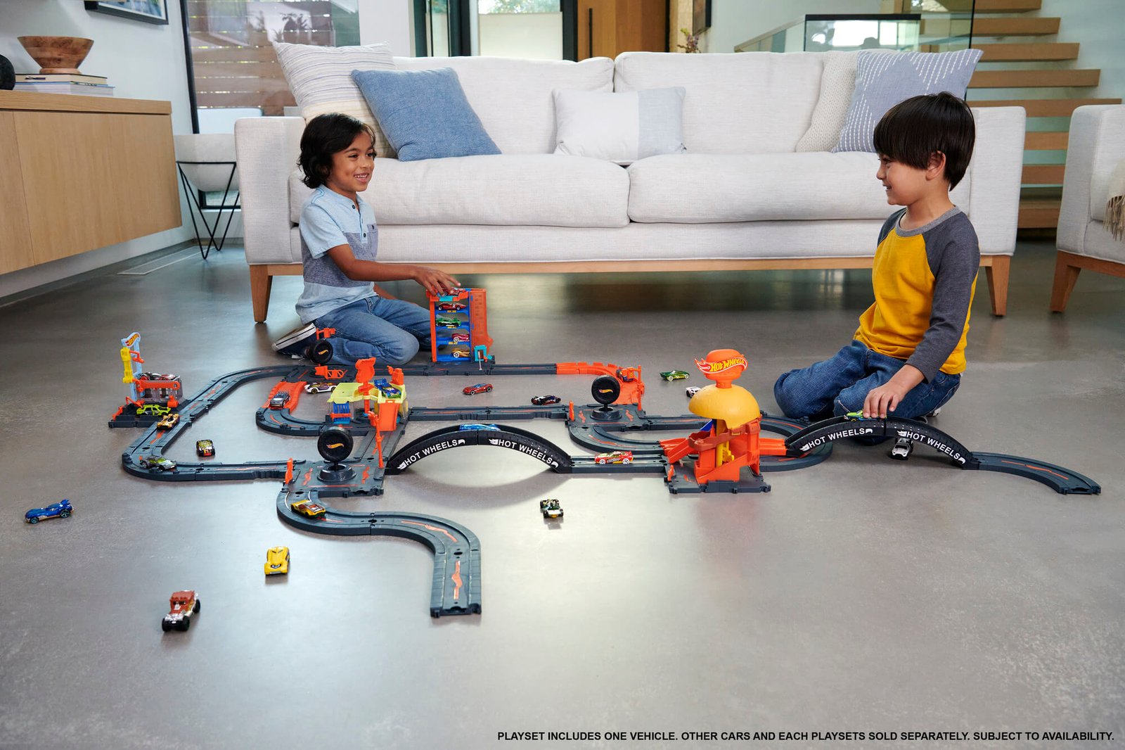 Vaikai žaidžia su dideliu miestu, sujungtu iš kelių atskirai parduodamų Hot Wheels City rinkinių