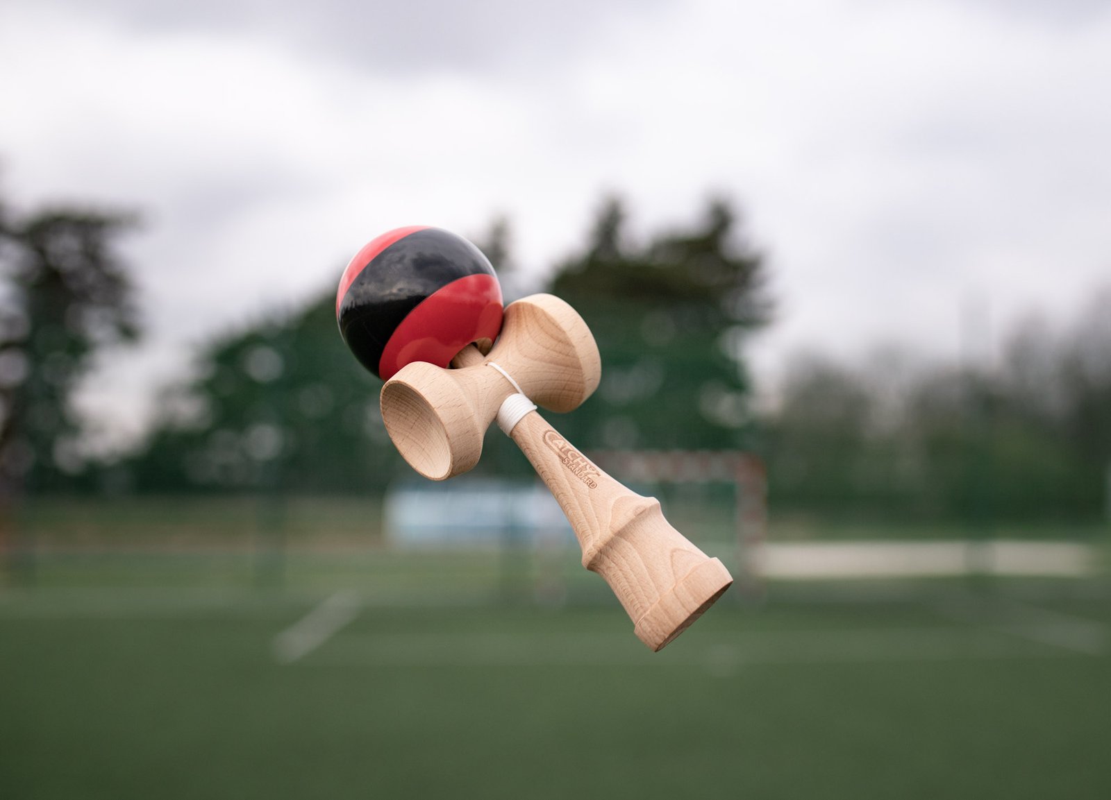 Raudona kendama ore lauke virš sporto aikštyno – kamuoliukas pagautas į kaušelį