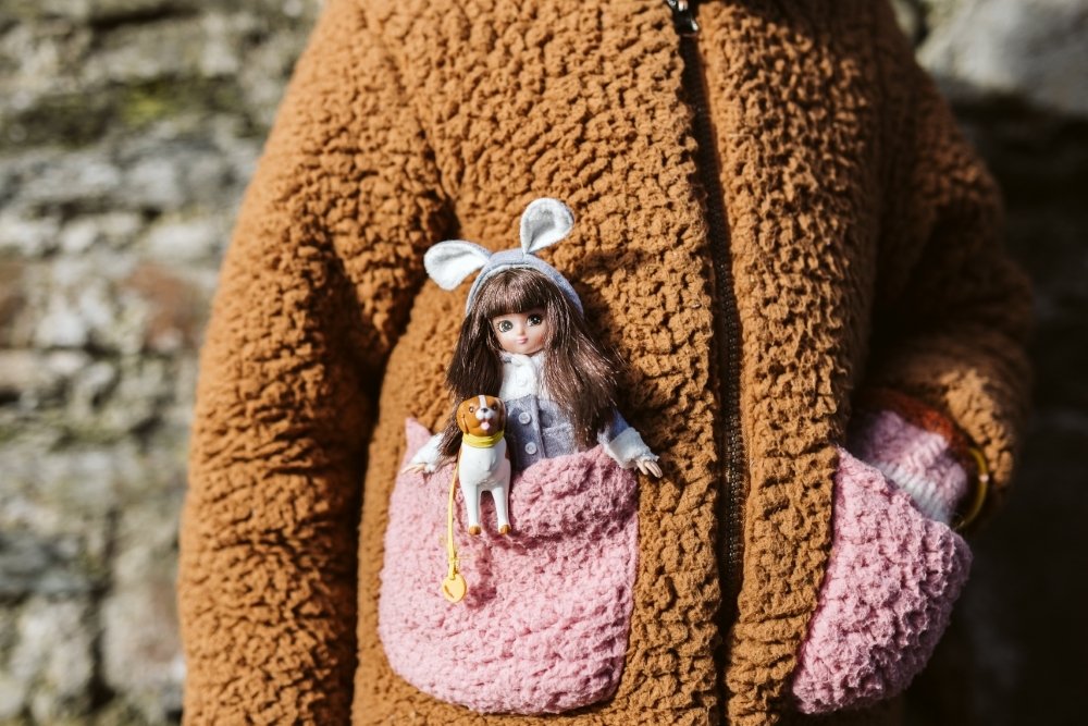Lottie lėlė vaiko palto kišenėje