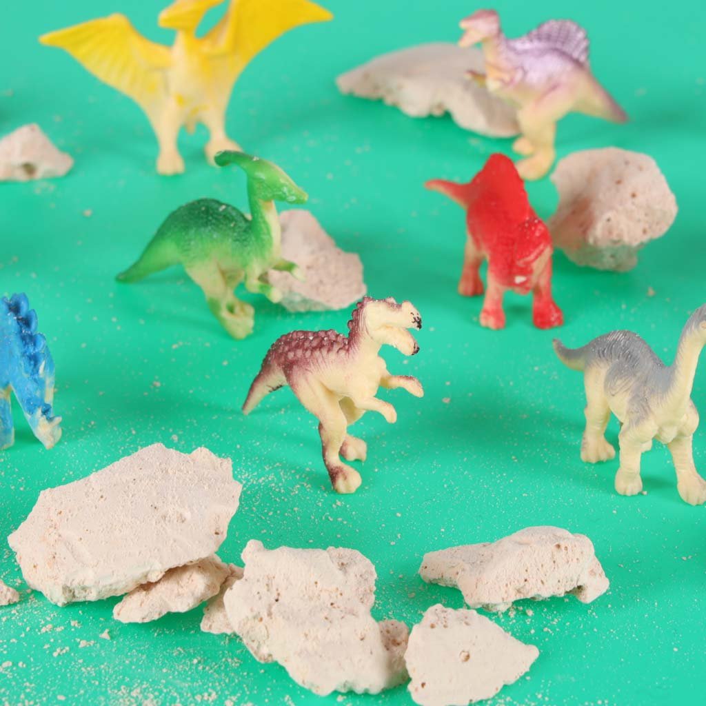 Iškastos dinozaurų figūrėlės tarp gipso gabalėlių
