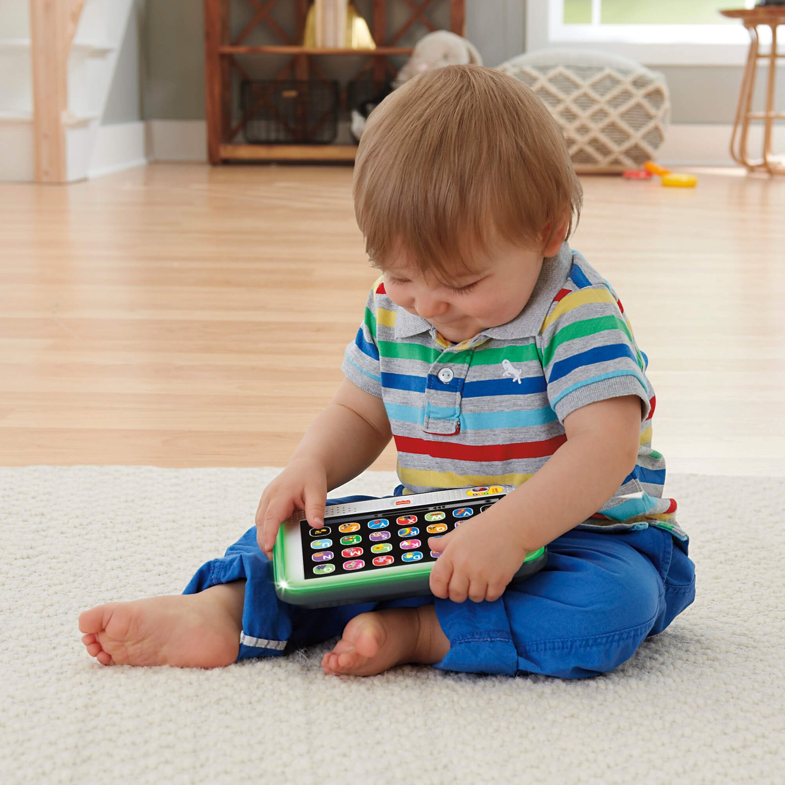Berniukas sėdi ant grindų ir žaidžia su Fisher-Price planšete