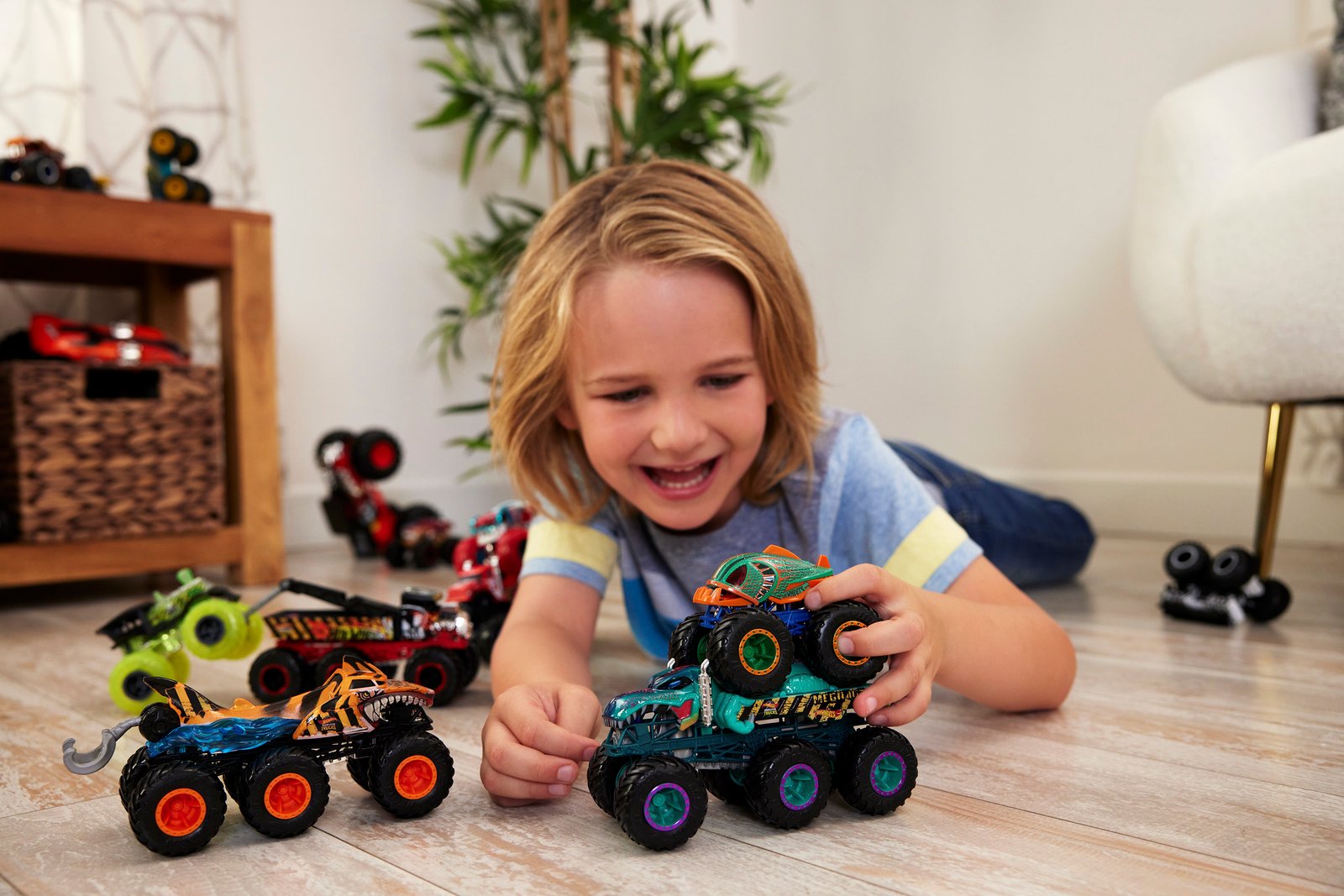 Vaikas ant grindų žaidžia su keliais Big Rigs ir Monster Trucks džipais