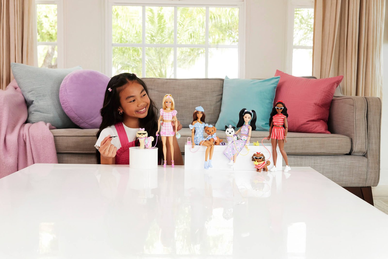 Mergaitė žaidžia su Barbie Twinning Looks serijos lėlėmis ir šuniukais